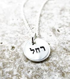 "This petite pendant necklace is just lovely! Hand stamped with your choice of name (example: Rachel) in Hebrew, this 1/2\" pendant necklace would make the perfect Bat Mitzvah, birthday, Hanukkah or anytime gift! Necklace will arrive with your choice of a 16\", 18\" or 20\" double rope cable chain. Please specify the following in the \"notes to seller\" at purchase: 1. Name you would like stamped Necklace suitable for 3-5 letters across, 5-10 letters around the outer edge. If you are unsure of h Meaningful Round Pendant Nickel-free Charm Necklace, Silver Charm Necklace With Custom Name And Round Pendant, Silver Charm Necklace With Custom Name On Round Pendant, Custom Name Silver Charm Necklace With Round Pendant, Silver Custom Name Charm Necklace With Round Pendant, Hand Stamped Round Pendant Charm Necklace, Silver Name Necklace With Charms, Silver Name Necklace With Charms And Round Pendant, Silver Name Necklace With Round Pendant And Charms