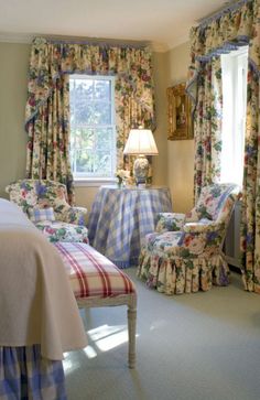 a bed room with a neatly made bed next to two chairs and a table in front of a window