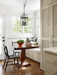 a dining room table with two chairs and a bench in front of the window,