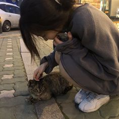 a woman petting a cat on the street