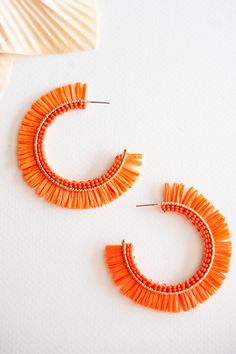 The Gracie Rattan Fan Hoops are the perfect accessory to elevate your tropical vacation style. These colorful rattan hoop earrings exude a playful and vibrant charm that complements any summertime outfit. Handcrafted with intricate attention to detail, each earring features a unique fan-shaped design, adding a touch of whimsy and exotic flair. Made from sustainable rattan material, these lightweight hoops provide a comfortable fit without compromising on style. Whether you're strolling along the Bohemian Orange Hoop Earrings For Summer, Orange Small Hoop Earrings For Summer, Trendy Small Hoop Earrings For The Beach, Trendy Hoop Earrings For Vacation, Summer Orange Small Hoop Earrings, Orange Summer Earrings For Vacation, Handmade Orange Hoop Earrings For Summer, Orange Small Hoop Jewelry For Summer, Summer Vacation Hoop Earrings