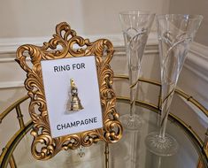 two wine glasses sitting on top of a table next to a sign that says ring for champagne