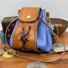 Looking for a stylish storage solution for your dice? Coin pouch for your Larp costume or D&D cosplay? This handcrafted leather bag might just be for you. Warm Tan hand stained vegtan leather main band with dark brown braided detail, and pale blue soft leather circle body section.  Brass coloured metalwork including a press popper to the front, eyelets on all the drawstring holes, 2 D-rings, and 2 semi precious stone charms. Size: approximately 130mm tall and wide Images show the bag empty and r Leather Pouch With Case Included For Gift, Gift Leather Pouch With Case Included, Leather Pouch With Case For Everyday Use, Adjustable Leather Bags For Personal Use, Brown Leather Hand-tooled Pouch, Blue Leather Artisan Shoulder Bag, Blue Artisan Leather Shoulder Bag, Blue Leather Pouch For Daily Use, Hand Tooled Brown Leather Pouch