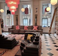 a living room filled with lots of furniture and large chandelier hanging from the ceiling