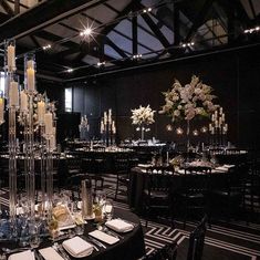 a room filled with tables covered in tall centerpieces