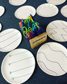 paper plates with scissors and markers on them sitting on a blue tablecloth covered floor