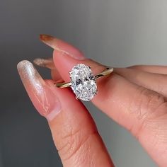 a woman's hand holding a diamond ring