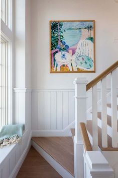 a painting hanging on the wall next to a stair case in a white painted room