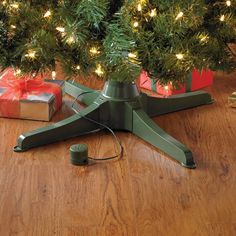 a christmas tree stand with presents under it on the floor next to a christmas tree