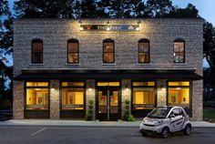 a small car parked in front of a brick building with windows lit up at night