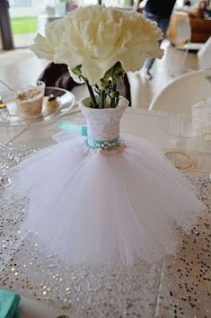 a white flower in a vase on a table with sequins and sparkles