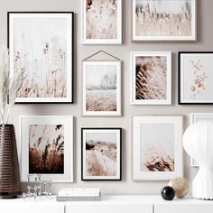 a white dresser topped with pictures and vases next to a wall covered in plants