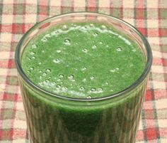 a green smoothie in a glass on a checkered tablecloth with water droplets