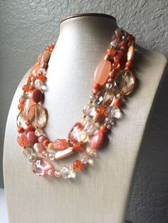 16 Inch Necklace with a 4 inch gold extender chain and gold lobster clasp. Coral and peach crystals and beads adorn this chunky 3 strand necklace. I also added in some clear glass crystals for some shimmer :-) Thank you for supporting American small business! 100% handmade. *Smoke and pet free home!* Hate to wait? Me too! I ship 6 days a week. Thank you for browsing my store! Check out my other items here: https://www.etsy.com/shop/PolkaDotDrawer?ref=si_shop Elegant Orange Beaded Crystal Necklace, Peach Faceted Round Beads Jewelry, Peach Colored Jewelry With Colorful Round Beads, Peach Beaded Jewelry With Round Beads, Chunky Necklaces Statement, Peach Crystals, Native Necklace, Necklaces Statement, Autumn Necklace