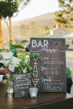 a wooden sign sitting on top of a table next to a vase filled with flowers