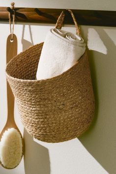 a wooden spoon hanging from the side of a wall next to a basket with towels