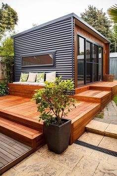 a small house sitting on top of a wooden deck next to a planter filled with flowers