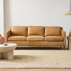 a living room with a couch, table and vases on the floor in front of it