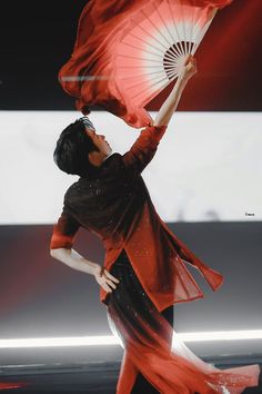 a woman holding an umbrella while standing on top of a stage