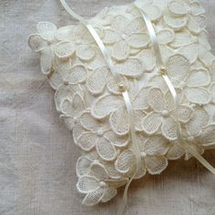 a white pillow on a bed with ribbon around the edges and buttons at the bottom