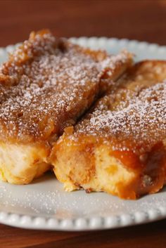 two pieces of cake sitting on top of a white plate covered in powdered sugar