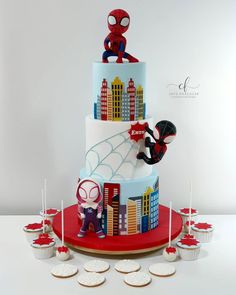 a spiderman themed cake with cupcakes and cookies