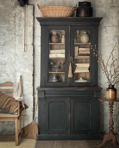 an old fashioned china cabinet with glass doors and shelves on the top, next to a wooden chair