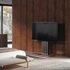 a large flat screen tv sitting on top of a wooden stand next to a bed