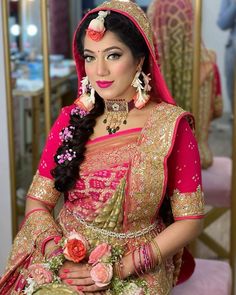 a woman in a pink and gold bridal outfit sitting on a chair with flowers in her hair