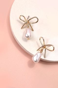 Pearl Dangle Gold Bow Drop Earrings, an exquisite blend of sophistication and charm. These earrings showcase a delicate gold bow design adorned with lustrous pearls, creating a timeless and elegant accessory. The pearl dangles add a touch of refinement and movement, making these earrings perfect for both formal events and everyday wear. Product Details:Width: 1" Length: 1.25"Earring back: PostMetal finish: gold PlatedProduct: Lead & Nickel CompliantAnti-tarnish: Double E-coating Elegant Rose Gold Earrings With Bow, Elegant Rose Gold Bow Earrings, Gold Feminine Pearl Earrings For Party, Feminine Gold Pearl Earrings For Party, Formal Pearl Jewelry With Bow, Formal Pearl Drop Earrings With Bow, Formal Bow Drop Pearl Earrings, Formal Pearl Earrings With Bow Detail, Formal Pearl Earrings With Bow