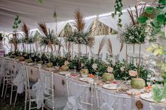 a long table set up with flowers and greenery for an outdoor wedding or reception