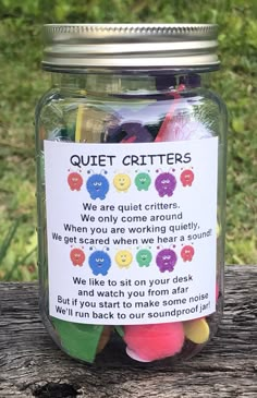 a jar filled with colorful candies sitting on top of a wooden table next to grass