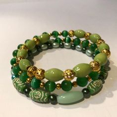 Green memory wire bracelet made from:  memory wire green ceramic beads 6 mm cats eye beads Green oval glass pearls gold spacer beads Green Stackable Beaded Bangle Bracelets, Green Stackable Bangle Beaded Bracelets, Green Spiritual Bracelet With Spacer Beads, Green Wrap Bracelet With Round Beads As Gift, Green Wrap Bracelet With Round Beads For Gift, Green Wrap Bracelet With Round Beads, Adjustable Green Wire Wrapped Bracelet, Green Beaded Bangle With Spacer Beads, Green Beaded Bangle Bracelets With Spacer Beads