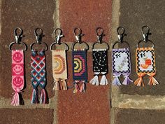 six key chains with tassels hanging from them on a brick wall next to each other