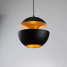 a black and yellow pendant light hanging from a ceiling in a room with white walls