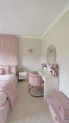 a bedroom with a pink bed, dresser and mirror in the corner on the wall