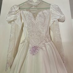 a white wedding dress with long sleeves and flowers on the skirt is displayed in front of a box