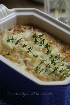 a casserole dish with cheese and parsley in a blue container on a table