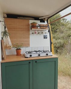 a small kitchen with green cupboards and a stove top oven in the back ground