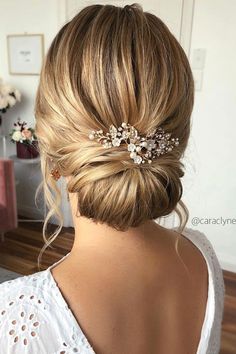 a woman with her hair in a low bun and some flowers on the back of her head