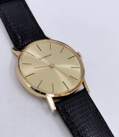 A fairly rare men's (unisex) 14k solid gold Swiss DUGENA watch with the classic Bauhaus look, with a gold punch on caseback, manual winding watch with a gold color dial, gorgeous, completely original, with lizard calf leather strap. The reverse is engraved, the watch is in good working condition, almost unworn pristine condition considering age, no scratches on the glass and case. Dates: 1979 Case size: 34 mm Total weight: approx. 29g A true classic, worth collecting! PLEASE NOTE: ALL MY WATCHES Antique Yellow Gold Watches For Business, Classic 14k Yellow Gold Watch, Gold Business Jewelry And Watches With Round Dial, Gold Jewelry And Watches With Round Dial For Business, Gold Engraved Business Watches, Engraved Gold Business Watches, Antique Gold Watch For Business, Formal Yellow Gold Analog Watches And Jewelry, Formal Yellow Gold Analog Jewelry And Watches