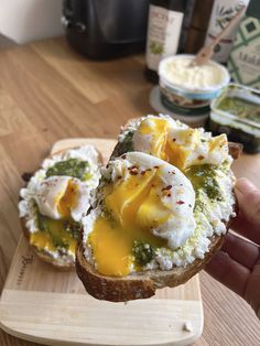 someone is holding up a piece of bread with eggs on it and pesto sauce