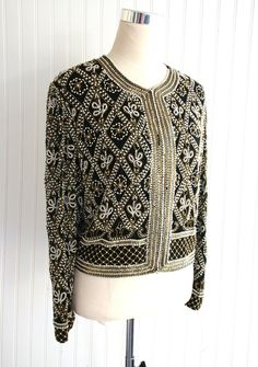 "This is a VERY heavily beaded cocktail party jacket.  There are some missing pearls along the neckline and down the front.   It is otherwise in beautiful conditon.  Marked size L 44\" total bust 17\" shoulder  19 1/2\" nape to hem  Purveyor's Note: We have searched far and wide, wrestled bears, braved the cold, traversed mountain ranges, fought pirates, swam with sharks and eaten at many a questionable road side taco stand to provide our customers with one of a kind vintage pieces.  Know that whichever piece you choose to make your own has its own story and has traveled through time to get to you.  Though we strive to provide the absolute best, \"pristine\" vintage pieces are rare birds, if not altogether non-existent.  That being said, please understand that part of buying and wearing vi Elegant Fitted Hand-embellished Outerwear, Elegant Fitted Hand Embellished Outerwear, Elegant Embroidered Party Outerwear, Festive Fitted Beaded Outerwear, Elegant Beaded Festive Outerwear, Vintage Beaded Evening Outerwear, Fitted Beaded Evening Outerwear, Elegant Beaded Long Sleeve Outerwear, Elegant Long Sleeve Beaded Outerwear