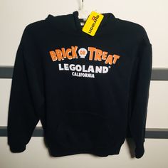 Legoland California Brick Or Treat Dragon Kids Hoodie Medium Front Says Brick Or Treat And The Back Of The Hoodie Has The Lego Dragon Dresses As A Mummy. So Cute. This Is A Unisex Size Medium And Its About 17" Across The Chest Brand New With Tags Rare Sold Out Hoodie !! Black Halloween Hoodie With Letter Print, Halloween Cotton Sweatshirt With Adjustable Hood, Orange Hooded Hoodie With Letter Print, Orange Hooded Sweatshirt With Letter Print, Black Halloween Top With Drawstring Hood, Black Hooded Tops For Halloween, Black Halloween Hoodie Top, Lego Shirts, Lego Dragon