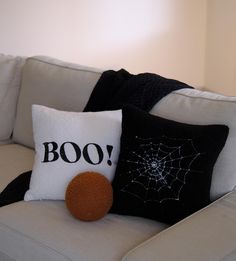 two black and white pillows sitting on top of a couch next to a spider web pillow