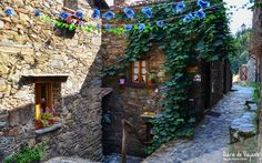 an alleyway with stone buildings and vines growing on the walls, along with potted plants