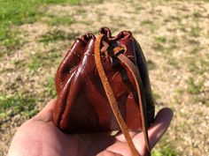 a hand holding a small brown purse in it's palm