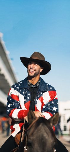 a man wearing an american flag jacket riding a horse