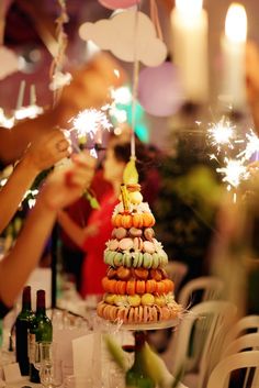 people holding sparklers over a table with food on it