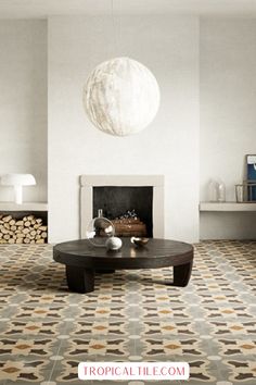 a living room with white walls and flooring has a round coffee table in front of the fireplace